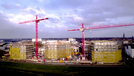 Revelación-Aérea-Ascendente-Del-Barrio-De-Noorderhaven-Detrás-De-Grúas-Rojas-Que-Se-Elevan-Sobre-Tres-Torres-Residenciales-En-Construcción-Envueltas-En-Andamios