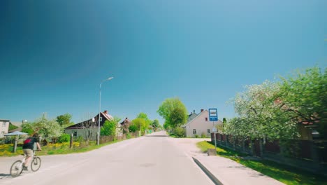 Rural-village-road-pov-in-the-Baltics-with-biker-countryside-houses