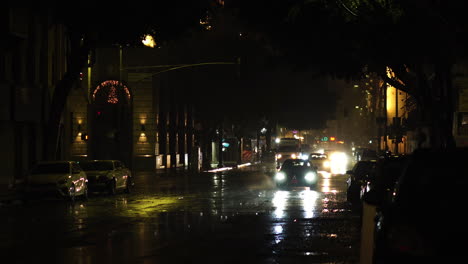 Street-Traffic-on-Rainy-Night-in-Downtown-Los-Angeles,-California-USA,-Car-Lights-and-Reflections-on-Road