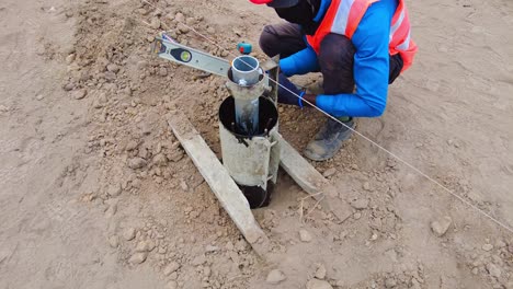 African-construction-worker-installing-and-leveling-concrete-pile-frame-mould-in-Jambur,-Gambia