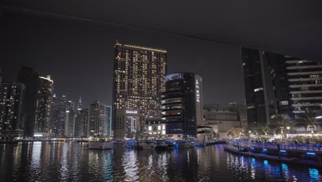 Night-cruise-on-Dubai-Marina-canal,-revealing-the-vibrant-downtown-area