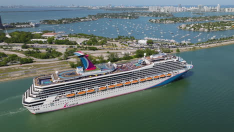 AERIAL-Cruise-liner-moving-through-the-Main-channel-of-sunny-Miami,-Florida,-USA