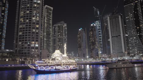 Night-cruise-on-Dubai-Marina-canal,-with-a-view-of-the-illuminated-Dubai-Marina-Mosque