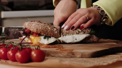 Woman-chef-cutting-a-crusty-sandwich-with-a-sharp-knife-in-a-kitchen