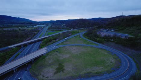 Aerial-evening-shot-of-highways-and-semi-trucks-on-I-80-in-Pennsylvania-with-surrounding-greenery