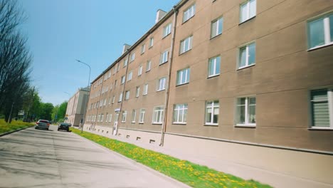 Wide-grey-brown-soviet-apartment-buidlng-in-Daugapvils-with-firemen-car-passing-by