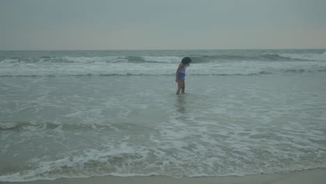 Woman-running-joyfully-into-the-ocean-waves-at-the-beach,-daytime-shot