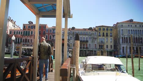 Vista-Fluida-Del-Gran-Canal-Y-Gente-Esperando-En-El-Muelle-Para-Un-Transporte-En-Lancha-Motora-En-Venecia