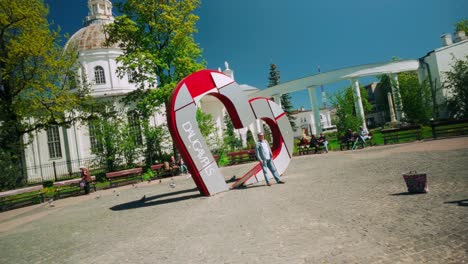 Punto-De-Referencia-Del-Corazón-Promocional-Turístico-De-Daugavpils-Con-Un-Hombre-Posando-Para-Su-Esposa