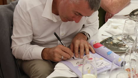 A-Father-of-a-Communicant-is-Penning-His-Thoughts-in-a-Dedication-Book-During-the-First-Communion-Ceremony-in-Zaragoza,-Spain---Close-Up