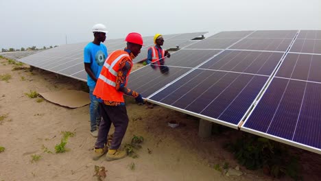 Trabajadores-Instalando-Paneles-Solares-Bifaciales-En-Un-Entorno-Africano-Al-Aire-Libre,-Centrándose-En-La-Energía-Sostenible