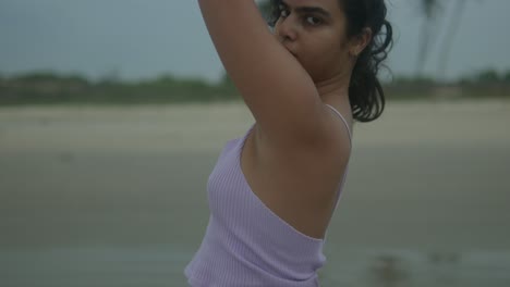 Young-woman-practicing-yoga-on-a-serene-beach-at-dusk,-focus-on-movement-and-tranquility