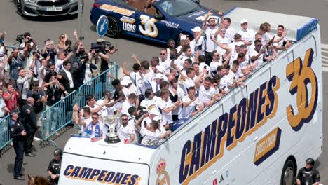 Riding-on-a-bus,-Real-Madrid-players-celebrate-winning-the-36th-Spanish-soccer-league-championship,-the-La-Liga-title-trophy,-at-Cibeles-Square,-where-thousands-of-fans-gathered-in-Madrid