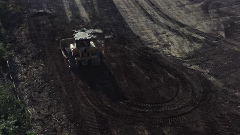 Bulldozer-moving-earth-creating-foundation-road-aerial-view-over-early-morning-sunrise-construction-site