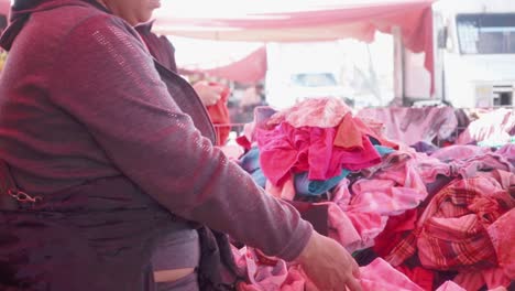 Woman-choosing-secondhand-clothes-from-a-pile-in-Tianguis