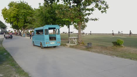 Blue-open-transport-car-driving-on-road-through-park-in-the-Philippines