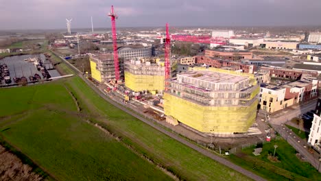 Aerial-panorama-of-red-cranes-rising-above-construction-site-Noorderhaven-part-of-urban-development-and-housing-neighbourhood-at-river-IJssel-floodplains