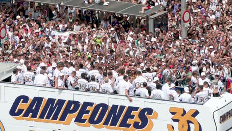 Riding-on-a-bus,-Real-Madrid-football-players-celebrate-winning-the-36th-Spanish-football-league-title,-the-La-Liga-trophy,-at-Cibeles-Square,-where-thousands-of-fans-in-Madrid,-Spain