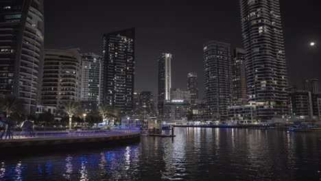 Night-cruise-on-Dubai-Marina-canal,-revealing-the-stunning-skyline
