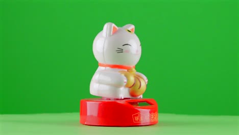 Maneki-neko-lucky-money-fortune-japanese-symbol-cat-souvenir-bowing-on-green-background-chroma-key-background-replacement-backdrop-objet-in-a-turntable-3d-spinning-loop