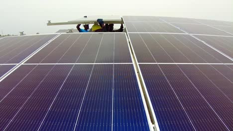 Static-shot-of-young-African-construction-workers-wearing-hard-hats-while-installing-solar-pv-panels-for-sustainable-renewable-energy-in-Jambur,-Gambia---west-Africa