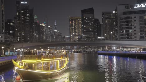 Experience-mesmerizing-Dubai-Marina-night-cruise,-passing-old-boat-beneath-overhead-bridge