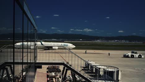 Avión-De-Greater-Bay-Airlines-En-La-Pista-Reflejándose-En-El-Cristal-De-La-Terminal