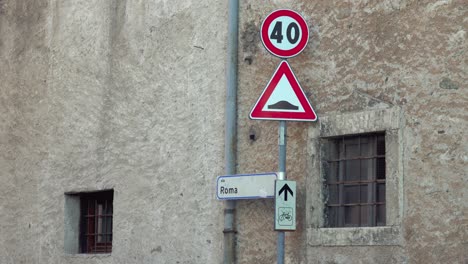 Zooming-in-on-Road-signs-attached-next-to-a-house-wall-in-via-Roma-in-Caldonazzo,-Trentino,-Italy