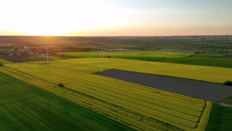 Aerial-view-of-fields-with-wind-turbines-and-village-at-sunset