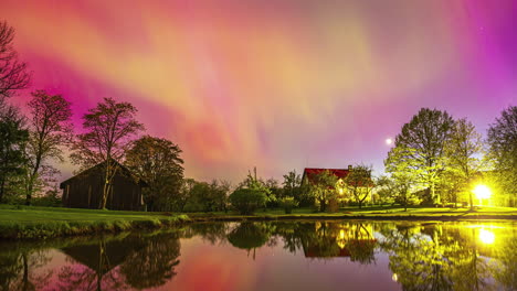 Lapso-De-Tiempo-De-La-Aurora-Boreal-Cambiando-De-Color-Sobre-Una-Serena-Casa-En-El-Lago-Por-La-Noche