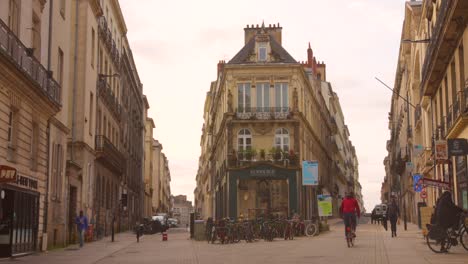 Una-Bulliciosa-Calle-En-Nantes,-Francia,-Con-Gente-Caminando-Y-Edificios-Antiguos-Al-Fondo.