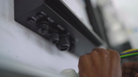 Closeup-view-of-hands-of-an-electrician-working-on-wires-of-solar-inverter-in-textile-industry-of-Pakistan