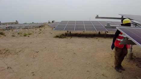 African-technicians-and-workers-installing-solar-panels-at-Jambur-Solar-PV-power-plant-wearing-safety-gears-panning-wide-shot