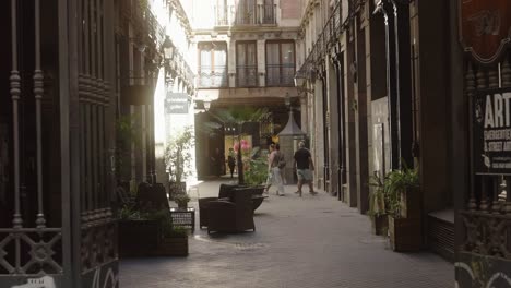 Gente-Caminando-Por-Las-Estrechas-Calles-De-La-Ciudad-Con-Cafeterías-Y-Restaurantes-En-Barcelona,-España