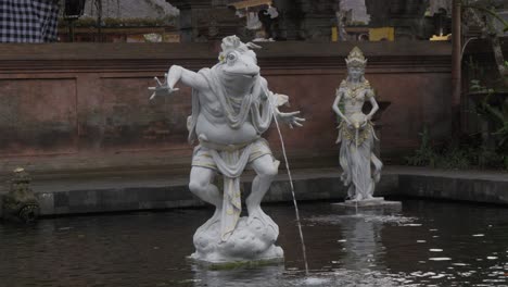 Una-Escultura-De-Fuente-única-Que-Representa-Una-Rana-Con-Cuerpo-Humano,-Chorreando-Agua-Por-La-Boca
