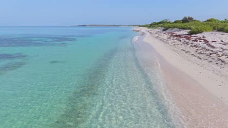 Turquoise-sea-waves-break-on-white-Caribbean-sand-beach,-aerial-forward