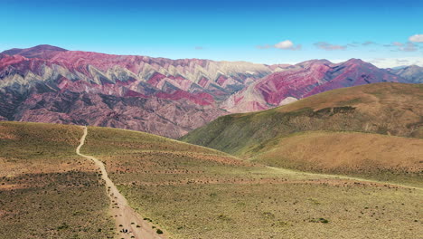 Dron-Avanza-Sobre-Un-Sendero-Mientras-Turistas-Viajan-Hacia-El-Mirador-Del-Cerro-De-Los-14-Colores,-También-Conocido-Como-Hornocal