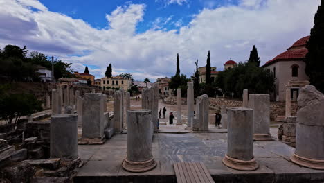 Tourists-stroll-between-column-of-Acropolis,-excavation-revealing-the-ancient-Roman-Agora