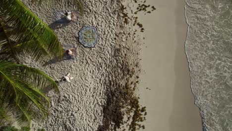 Top-view-of-tourists-doing-meditation-at-shore-of-tropical-beach-in-Spain