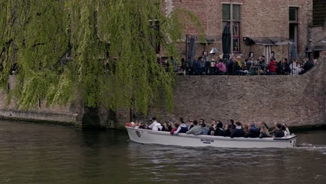 Tourists-Enjoying-Boat-Ride-On-Dijver-Canal-In-Bruges,-Belgium