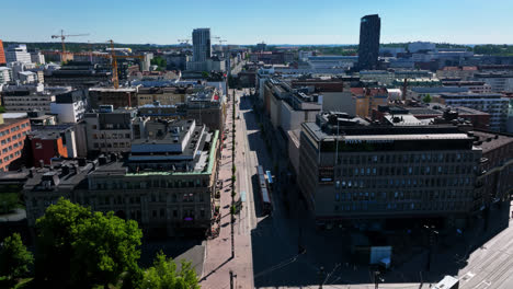 Drone-tracking-a-light-rail-on-the-streets-of-Tampere,-sunny-day-in-Finland