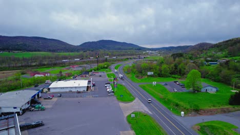 Spring-drone-view-of-a-truck-stop-entrance-in-Pennsylvania,-showcasing-trucks-and-green-surroundings