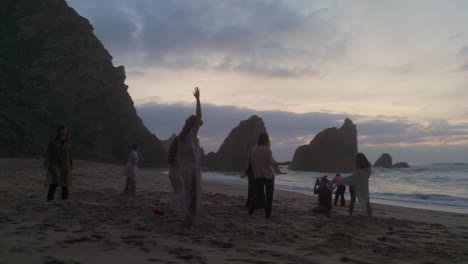 Mujeres-Bailando-Sobre-La-Arena-Con-Enormes-Acantilados-De-Fondo