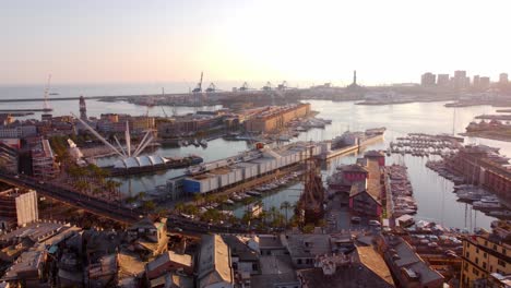 Genoa's-historical-center-at-sunset-with-bustling-port-and-rooftops,-aerial-view