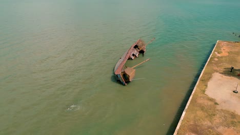 4K-Cinematic-nature-drone-footage-of-a-panoramic-aerial-view-of-an-abandonned-ship-on-the-island-of-Koh-Lanta-in-Krabi,-South-Thailand,-on-a-sunny-day-over-the-old-town-of-Lanta