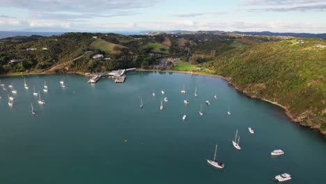 Boats-On-The-Tranquil-Water-Of-Matiatia-Bay-In-Auckland,-New-Zealand---Aerial-Pullback