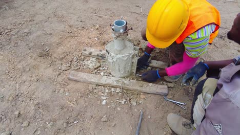 Construction-worker-in-bright-attire-removing-a-concrete-mould-from-a-pile-frame-at-a-building-site