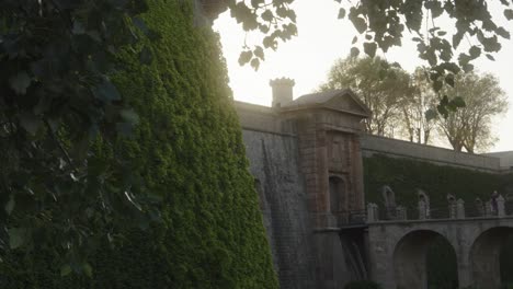 Scenic-medieval-bridge-entrance-with-wall-covered-in-plants-at-the-mirador-Montjuic-in-Barcelona,-Spain