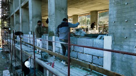 Construction-workers-stand-on-scaffolding