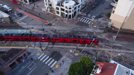 Red-color-Trolley-of-San-Diego-ride-through-downtown,-aerial-follow-view